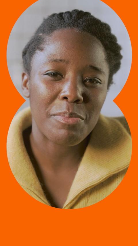 A woman with black hair wears a yellow zip sweater