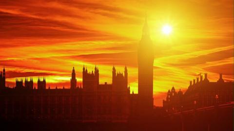 Silhouette of UK Parliament with late orange evening sun behind