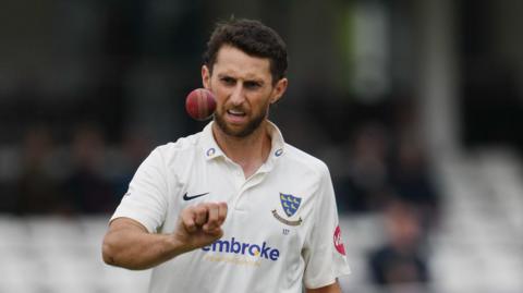 Fynn Hudson-Prentice tosses the ball in the air while bowling for Sussex