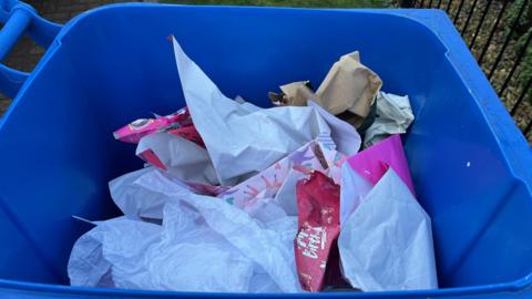 A blue bin containing paper