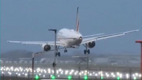 A plane prepares to touchdown on a runway with the landing lights switched on