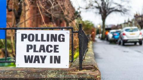 A generic image of a Polling Place Way In sign affixed to a railing in Scotland