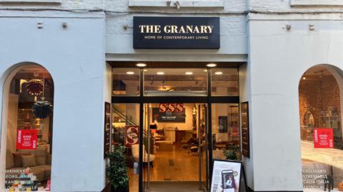 The outside of a shop with furniture inside, and a sign that says "The Granary, Home of Contemporary Living".