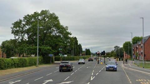 A Google Street View image shows a pedestrian crossing outside the Kings School on Wrexham Road in Chester. Some apartment buildings can be seen on the opposite side of the road.