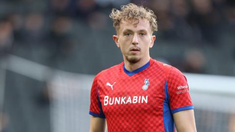 Michael Mellon wearing a red Oldham Athletic kit