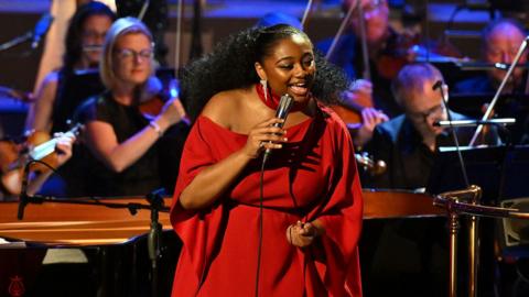 Samara Joy singing in front of an orchestra