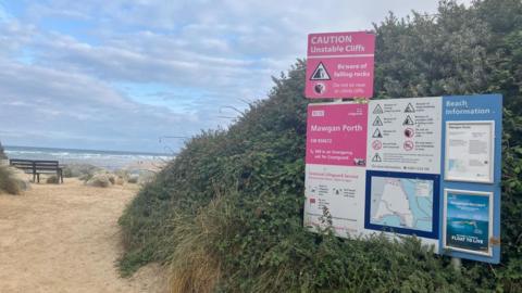 Mawgan Porth beach, showing the entrance to the beach and various warning signs about current etc. 