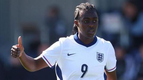 England player Michelle Agyemang, wearing the team kit, gives a thumbs-up gesture