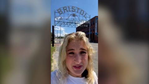 Eve Webster has blonde hair and stands in front of a sign that says Bristol