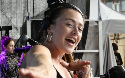 A young woman in a black bandana DJs on stage at the Bristol Harbour Festival