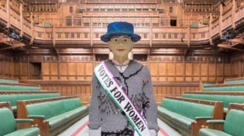 A life-size Lego model of a Suffragette woman stood in the centre of parliament, with rows of green seats and wooden panelling on the walls. 