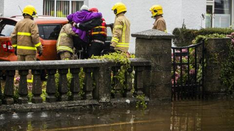 lady being rescued from floodwater