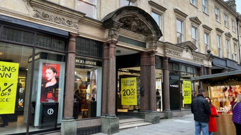 Image shows the outside of the department store Jolly's, with yellow 'Closing Down' signs in the windows. 