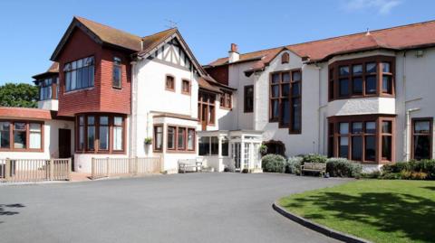 A multiple level care home building, with the brickwork a mixture of white and red.