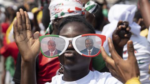 A supporter of the National Democratic Congress (NDC), the party of former president John Dramani Mahama, celebrate at the party's headquarters on December 8, 2024 in Accra, Ghana. They are wearing glasses in the party colours of red, white and green, with Mahama's photos on them.