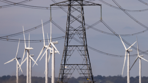 Wind turbines and power lines cut across the landscape of the Romney Marshes