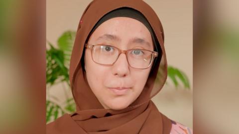 A women wears a brown hijab and brown glasses