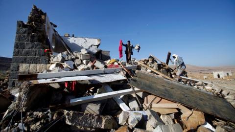 People inspect damage at the site of an air strike which hit a house where mourners had gathered for a funeral north of Yemen's capital Sanaa, on 16 February, 2017.