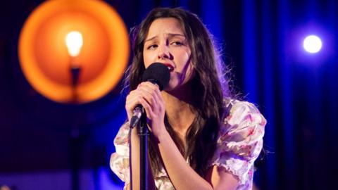 Olivia Rodrigo holding the microphone, singing at Radio 1 Live Lounge