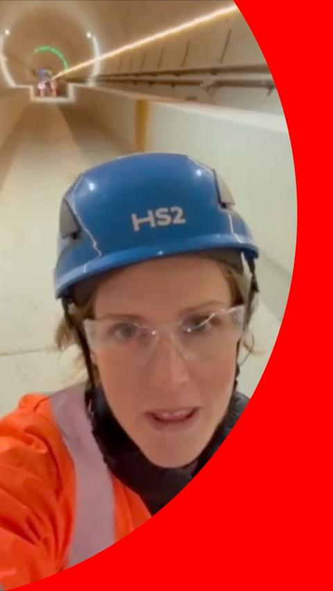 A woman wears a blue helmet and stands inside a long tunnel