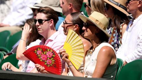 People fan themselves in the stands at Wimbledon. 
