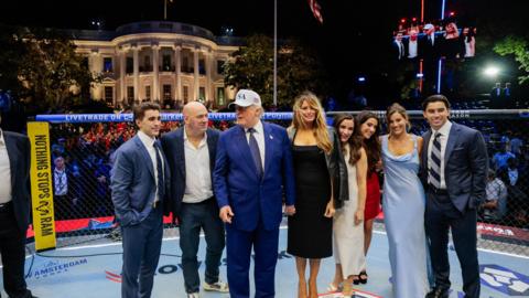 US President Donald Trump, US First Lady Melania Trump, UFC CEO Dana White and other guests stand inside the Octagon at UFC Freedom 250 on the South Lawn of the White House