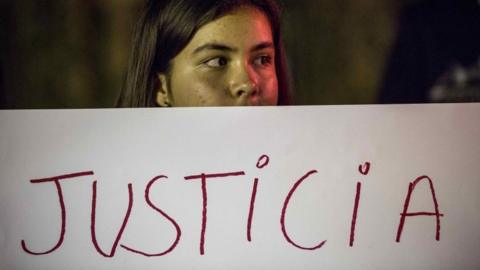 A woman holds a banner which reads: "JUSTICE" during a protest to honour the girls who lost their lives in a fire at a juvenile shelter in Guatemala