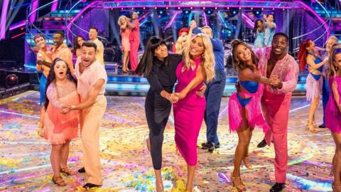 Strictly contestants Nitro and Ellie Goldstein with their partners on the Strictly dancefloor, as well as hosts Tess Daly and Claudia Winkleman.