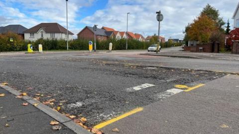Road with white markings fading and yellow spray paint on it.