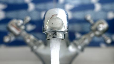 Close up image of a tap, with water coming out of the spout