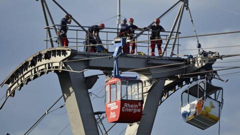 Firefighters assess the damage caused after a cable car struck a pillar in Cologne, Germany, 30 July 2017