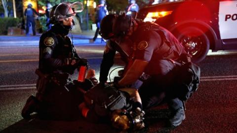 Police officers detain a demonstrator during a protest against police violence and racial injustice in Portland, Oregon, US