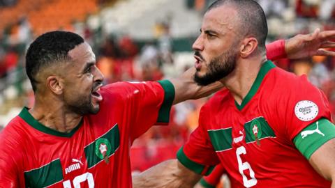 Morocco players Youssef En-Nesyri and Romain Saiss celebrate a goal against Tanzania