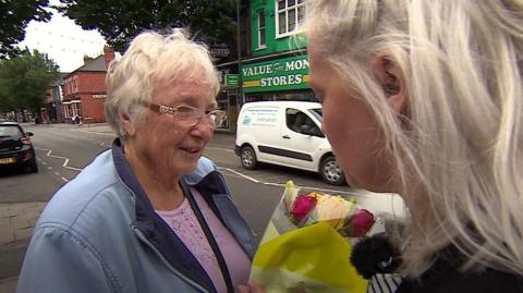 Woman giving a stranger a bouquet of flowers