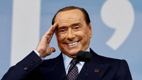 Silvio Berulsconi smiling and saluting