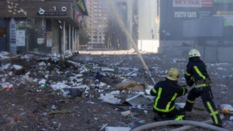 Firefighters work by a residential building hit by a missile strike in the morning in Kyiv on 26 February