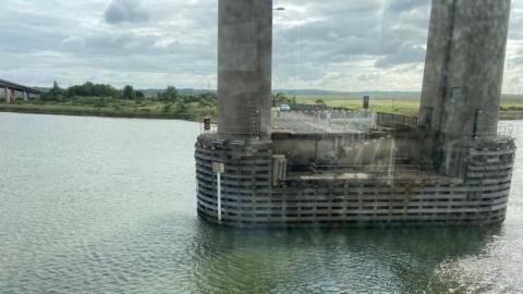A concrete base of a bridge stretching over water. 