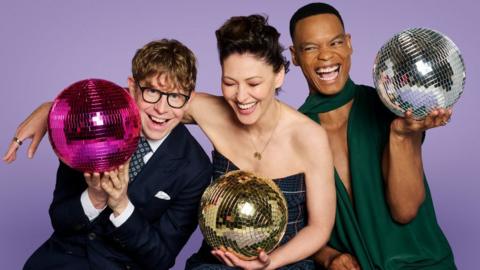 Josh Widdicombe, Emma Willis and Johannes Radebe holding glitter balls.