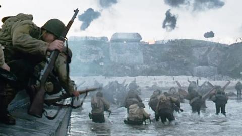 A still from Saving Private Ryan, 1998, Dreamworks Pictures, Directed by Steven Spielberg. Soldiers with guns stand in a mass body of water approaching a shore.