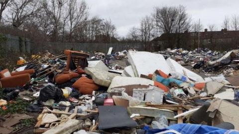 Piles of rubbish including sofas and mattresses inside the derelict car park at in Wealdstone South