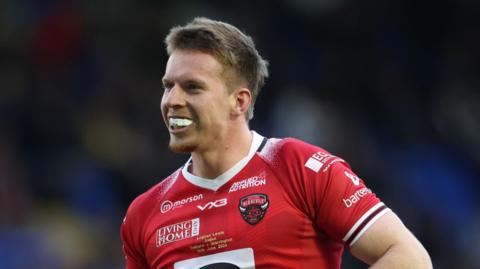 Loghan Lewis playing for Salford in 2024, with a big smile showing his mouth guard