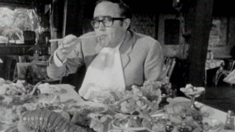 James Burke eating food with chopsticks in a restaurant.