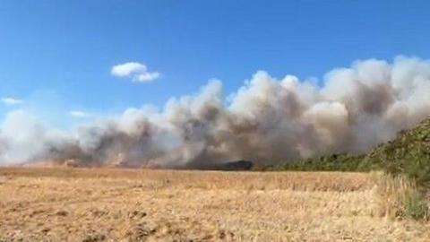 Smoke billows into the sky from a field used for farming. 