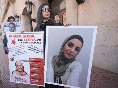A woman holds up posters showing pictures of Leqaa Kordia as Columbia students, professors and supporters gather in front of the university.
