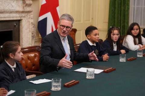 Prime Minister Keir Starmer speaking to students in the cabinet room in number 10 with the flag of the united kingdom behind him