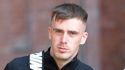 Declan Price arriving at court - he has short dark and is wearing a dark top. A Nike sports bag is slung over his shoulder.