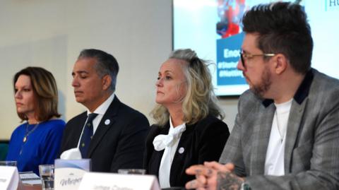 The families of the Nottingham attack victims sit at a table at a press conference