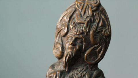 A closeup of the head of the Reih Bleeaney Vanannan trophy, which is a statue of the sea god Manannan, against a grey background.