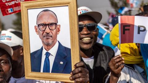 A Rwandan Patriotic Front (RPF) supporter holds a portrait of the Incumbent President of Rwanda and presidential candidate Paul Kagame during a campaign rally in Kigali, on July 12, 2024