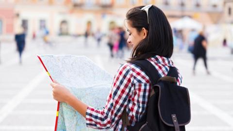 A young woman reading a map in a European city